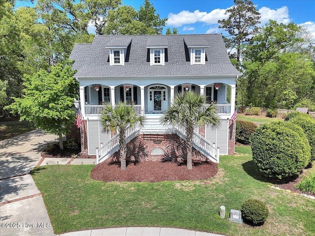 view of front facade featuring roof with shingles, covered porch, a front lawn, and stairway