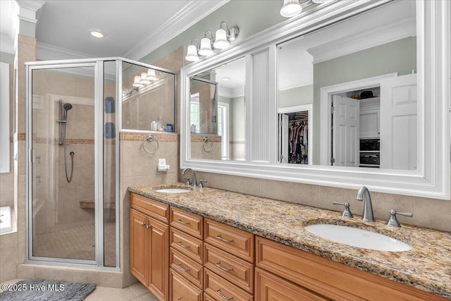 bathroom with a shower stall, crown molding, and a sink