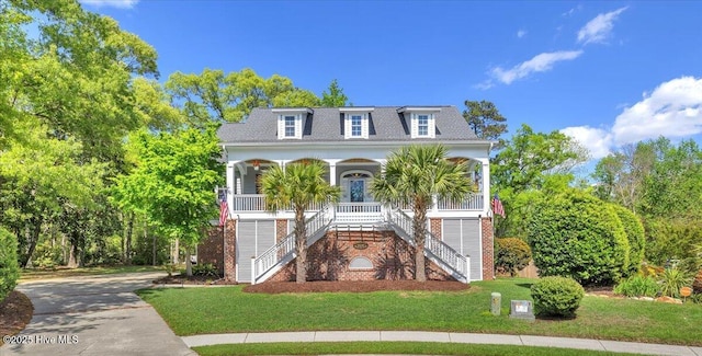 view of front of property featuring a front yard, a porch, stairs, brick siding, and roof with shingles