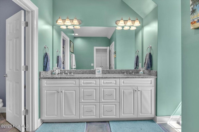 full bath featuring baseboards, a sink, toilet, double vanity, and tile patterned flooring