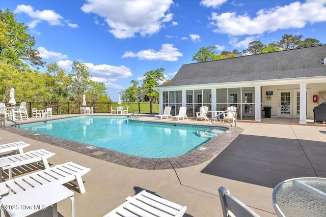 pool featuring a sunroom, a patio area, and fence