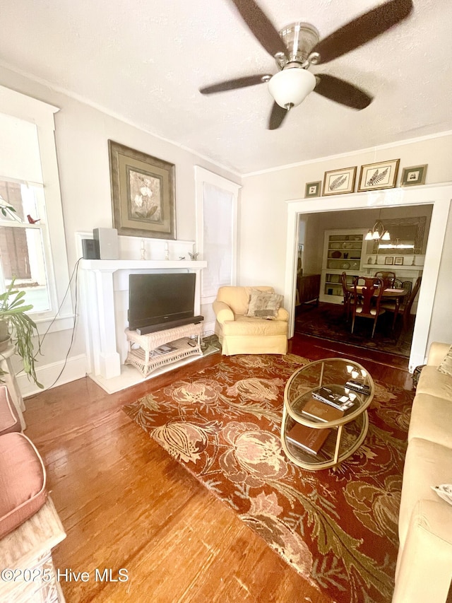 living area featuring ceiling fan, ornamental molding, and wood finished floors