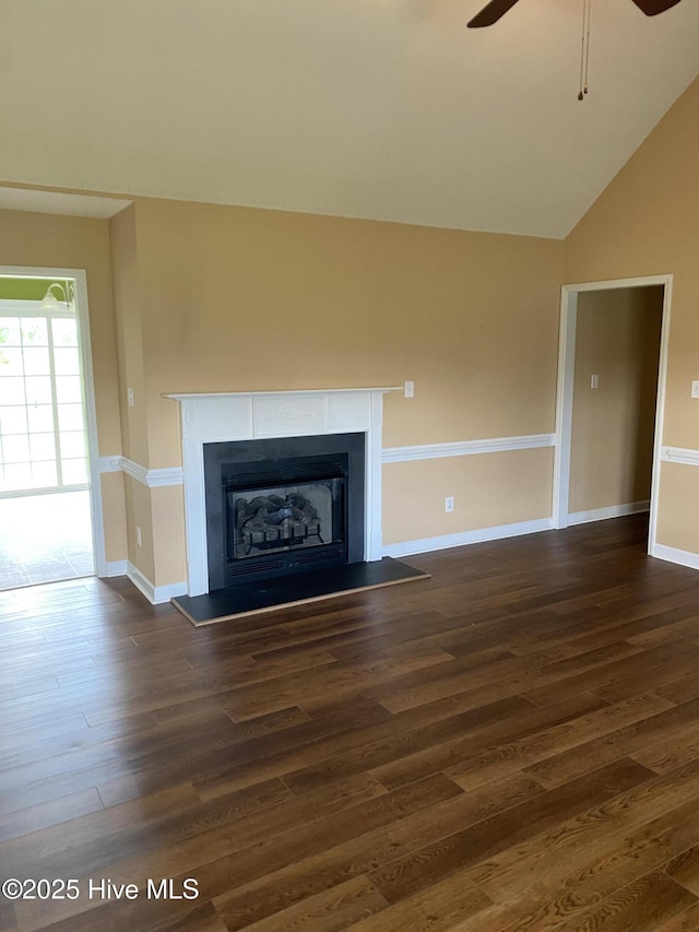 unfurnished living room with wood finished floors, baseboards, a ceiling fan, and a fireplace with raised hearth