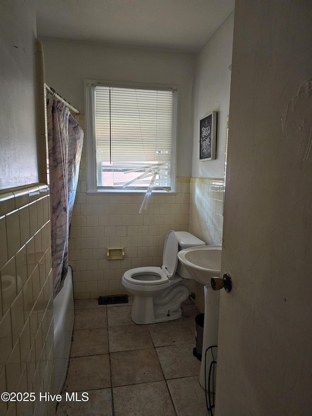 bathroom featuring visible vents, toilet, tile walls, a wainscoted wall, and tile patterned flooring