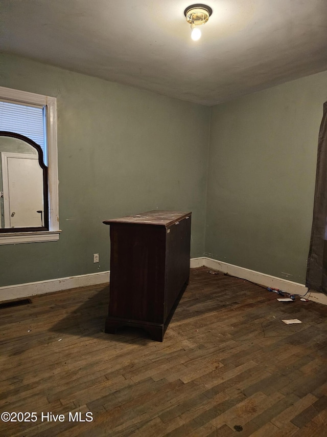 unfurnished office with dark wood-style flooring and baseboards