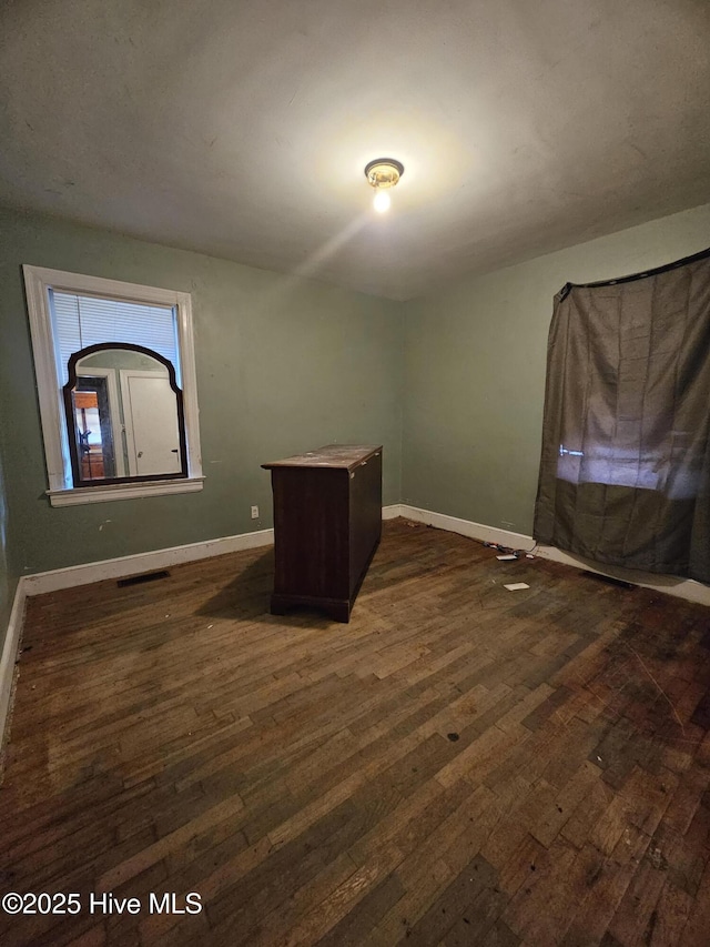 unfurnished room featuring visible vents, baseboards, and dark wood finished floors