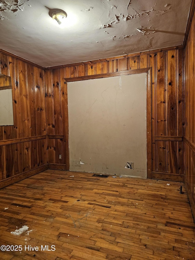 below grade area with wooden walls and hardwood / wood-style flooring