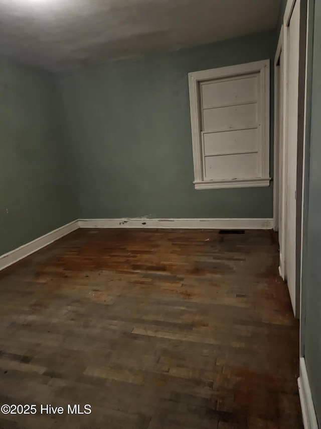 unfurnished room featuring dark wood-style floors and baseboards