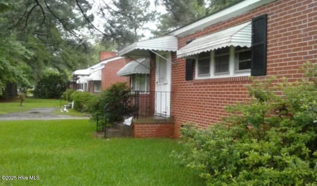 exterior space featuring a yard and brick siding