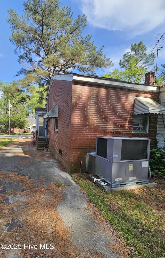 view of property exterior featuring brick siding, entry steps, central AC, and crawl space