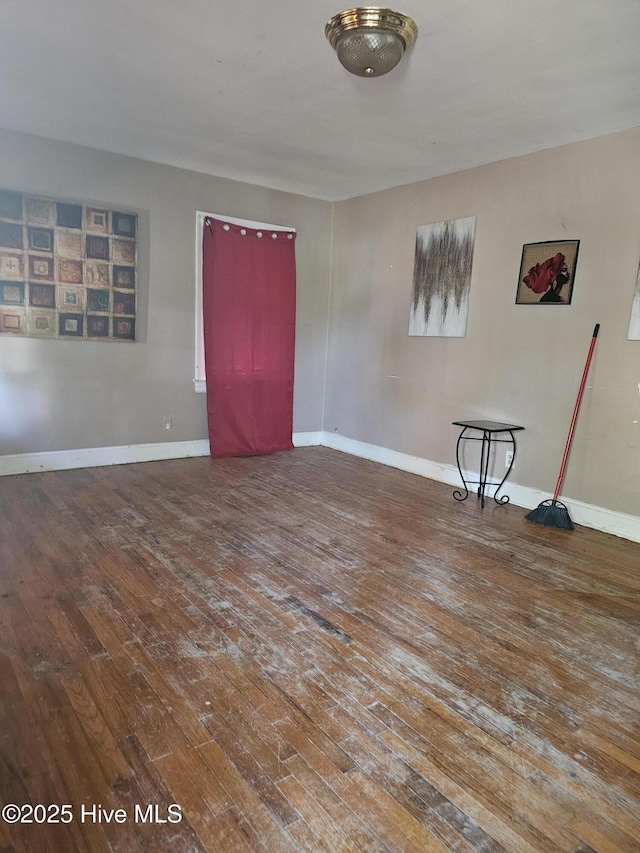 spare room featuring baseboards and hardwood / wood-style floors