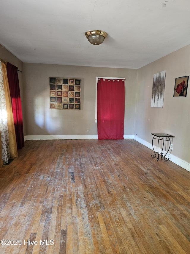 empty room featuring hardwood / wood-style flooring and baseboards