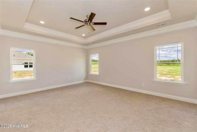 empty room featuring ornamental molding, visible vents, a raised ceiling, and baseboards