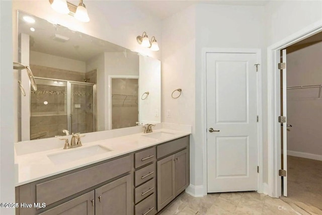 bathroom with double vanity, a walk in closet, a shower stall, and a sink