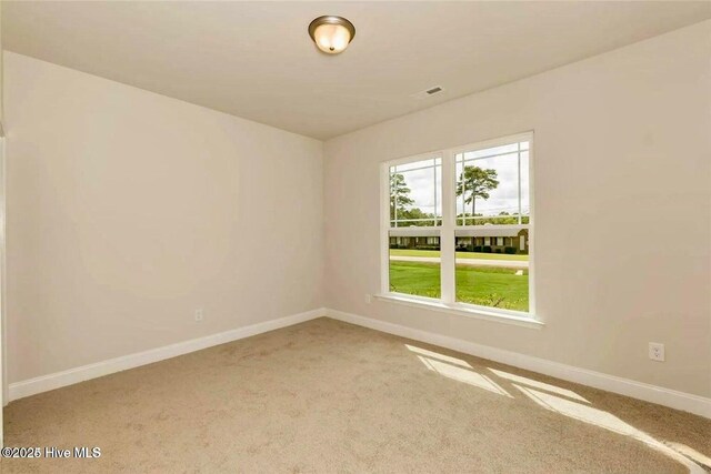 empty room with carpet, visible vents, and baseboards