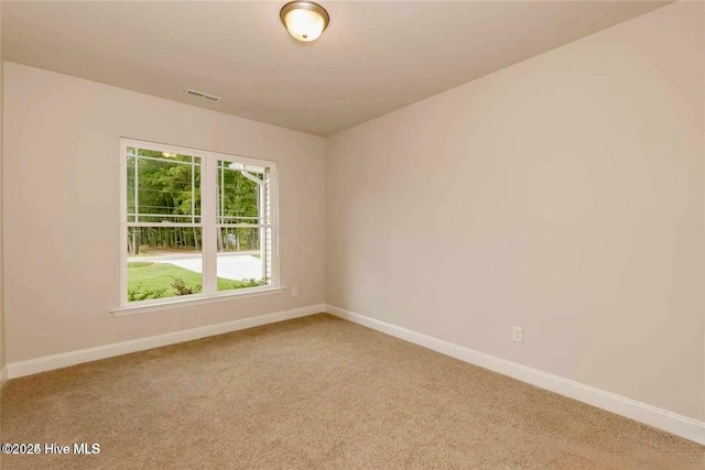 spare room featuring baseboards, visible vents, and light carpet