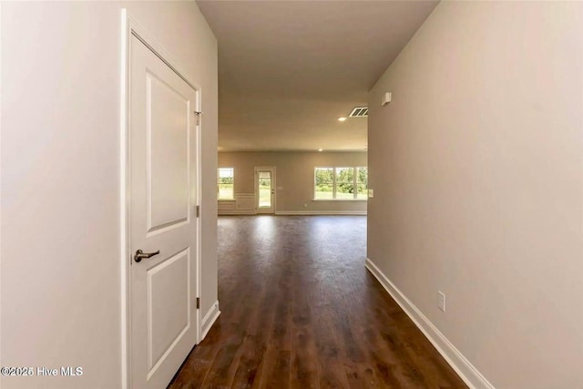 hall with dark wood-style flooring, visible vents, and baseboards