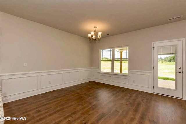 unfurnished room with dark wood-style floors, visible vents, a wainscoted wall, and a notable chandelier