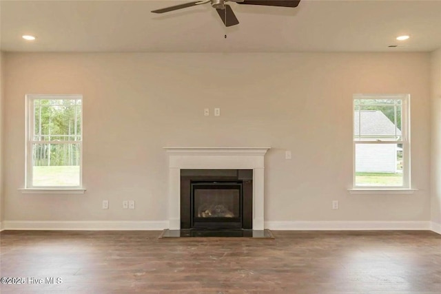 unfurnished living room with wood finished floors, plenty of natural light, and a ceiling fan