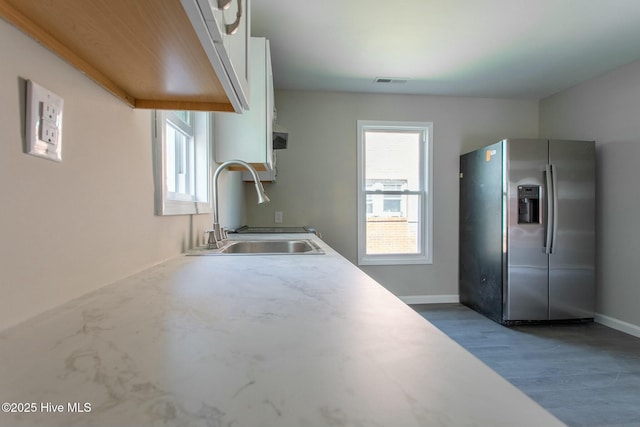 915 N Broad St, Edenton, NC 27932 - kitchen with stainless steel fridge with ice dispenser, a sink, white cabinetry, light countertops, and wood finished floors