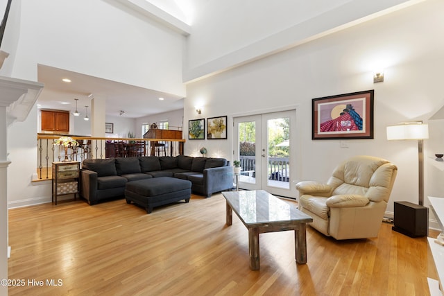 living room featuring recessed lighting, light wood-style floors, a high ceiling, and french doors