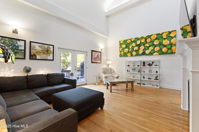 living room with french doors, light wood-type flooring, and a high ceiling