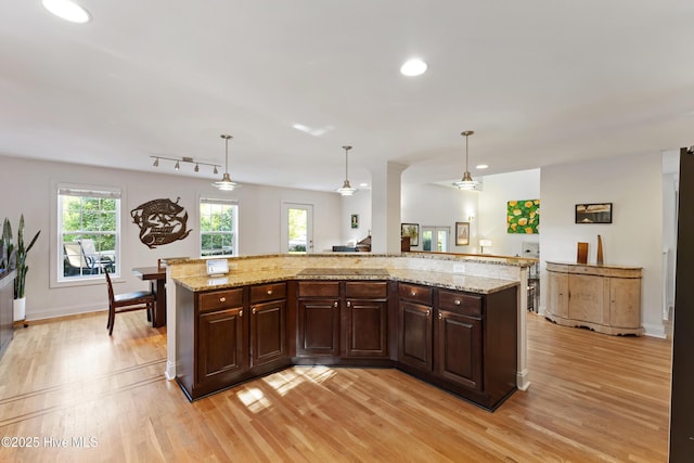 kitchen with recessed lighting, pendant lighting, light wood finished floors, and dark brown cabinetry