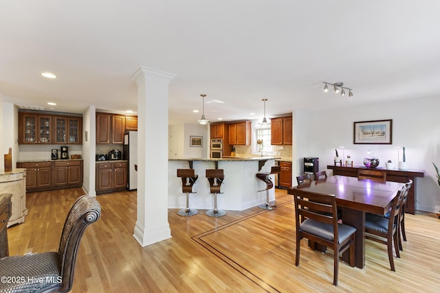 dining space with baseboards, light wood finished floors, ornate columns, and recessed lighting
