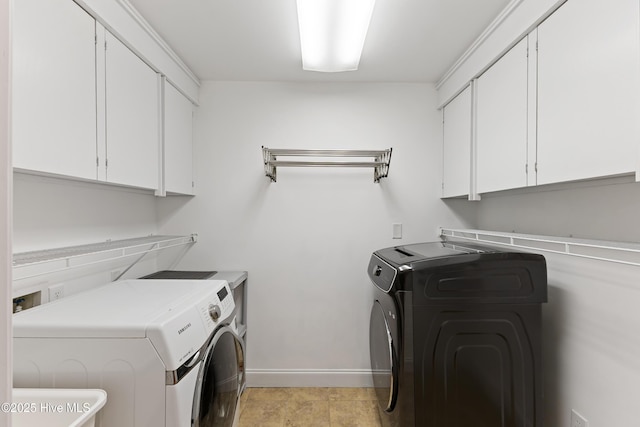 clothes washing area featuring cabinet space, baseboards, and separate washer and dryer