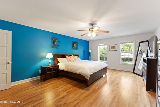 bedroom with baseboards, light wood finished floors, and a ceiling fan