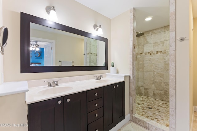 bathroom featuring tiled shower, double vanity, a sink, and ceiling fan