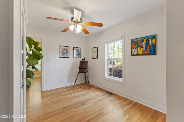 spare room featuring light wood-type flooring, baseboards, and a ceiling fan