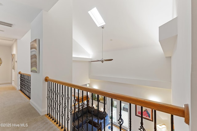 hall featuring baseboards, an upstairs landing, carpet floors, visible vents, and a skylight