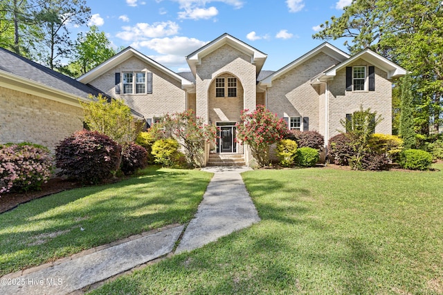 traditional-style home featuring a front yard and brick siding