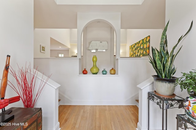 interior space featuring arched walkways, wood finished floors, and baseboards