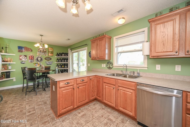 kitchen with a peninsula, light countertops, visible vents, stainless steel dishwasher, and a sink
