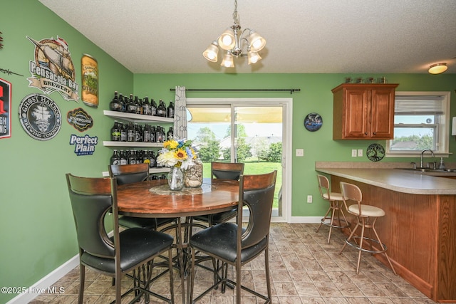 dining area with baseboards, a chandelier, and a textured ceiling