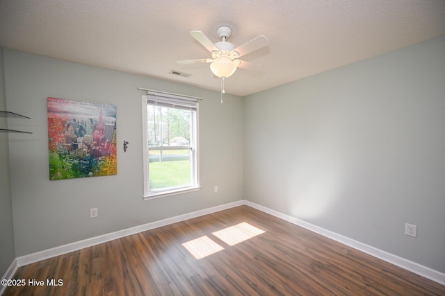 spare room featuring dark wood-type flooring, visible vents, baseboards, and ceiling fan