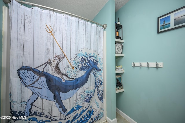 full bath with baseboards and a textured ceiling