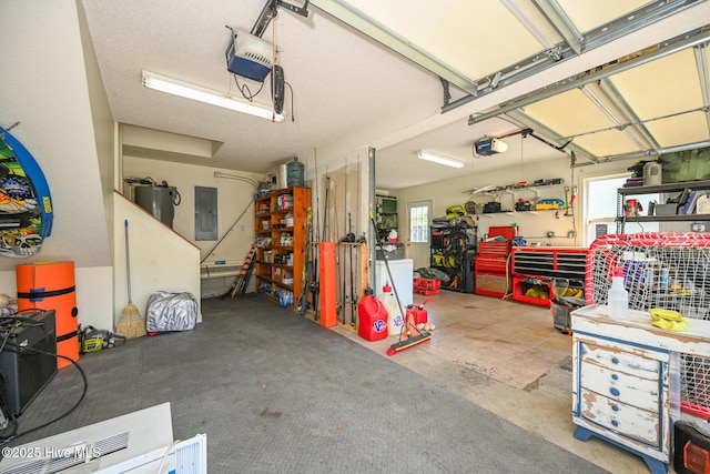 garage featuring a garage door opener, a workshop area, and electric panel