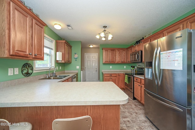 kitchen with visible vents, a notable chandelier, a sink, light countertops, and appliances with stainless steel finishes