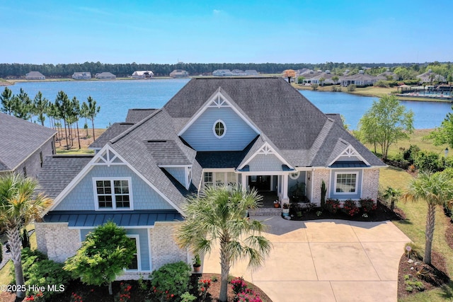 view of front of house featuring a shingled roof, brick siding, and a water view