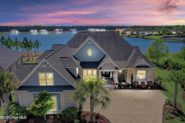 view of front of house with brick siding, roof with shingles, a water view, and a standing seam roof