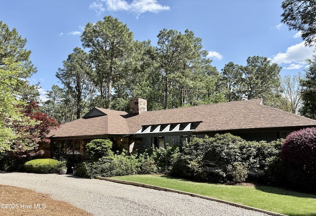 207 Bump A Long Ln, Southern Pines, NC 28387 - view of front facade featuring board and batten siding, a chimney, a front lawn, and roof with shingles