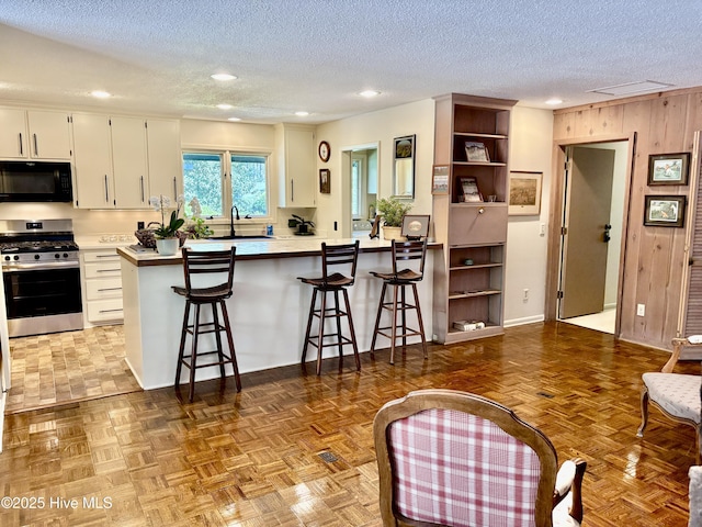 207 Bump A Long Ln, Southern Pines, NC 28387 - kitchen featuring a textured ceiling, gas range, a breakfast bar area, and black microwave
