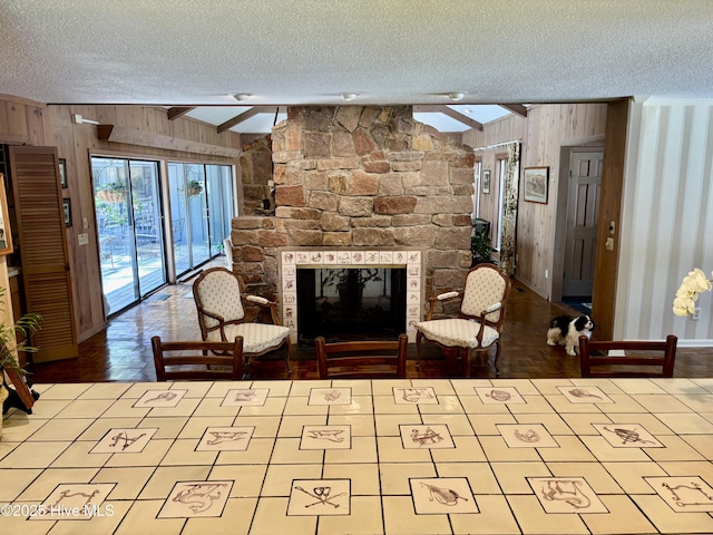 207 Bump A Long Ln, Southern Pines, NC 28387 - living area with vaulted ceiling with skylight, wood walls, a stone fireplace, and a textured ceiling