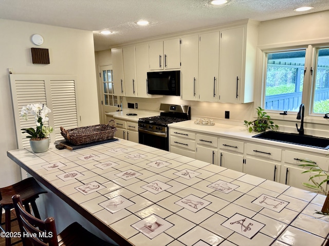 207 Bump A Long Ln, Southern Pines, NC 28387 - kitchen featuring a breakfast bar, black microwave, stainless steel gas range oven, white cabinets, and a sink