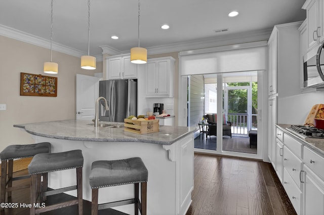 kitchen with ornamental molding, stainless steel appliances, a kitchen bar, and white cabinetry