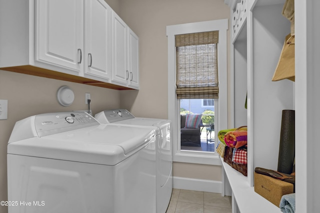 washroom with cabinet space, baseboards, washing machine and dryer, and light tile patterned floors