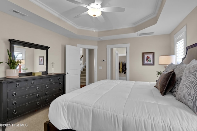 bedroom with a ceiling fan, visible vents, ornamental molding, and a raised ceiling